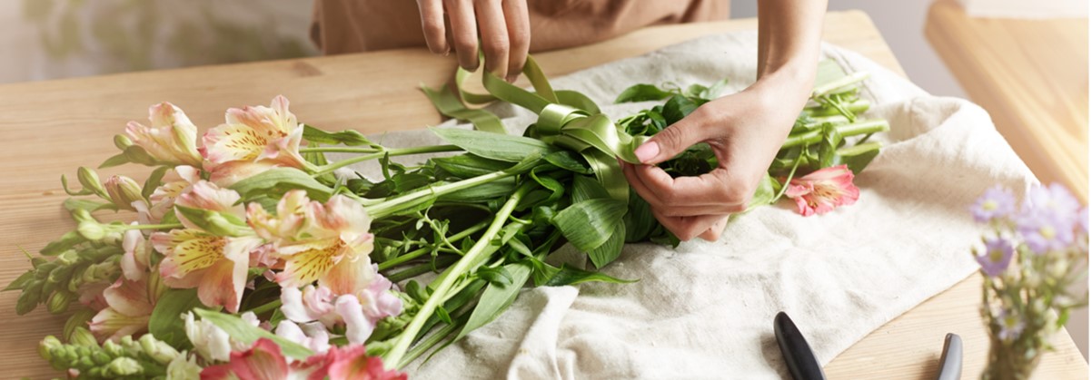 close-up-young-female-florist-tying-ribbon-bouquet-workplace.jpg